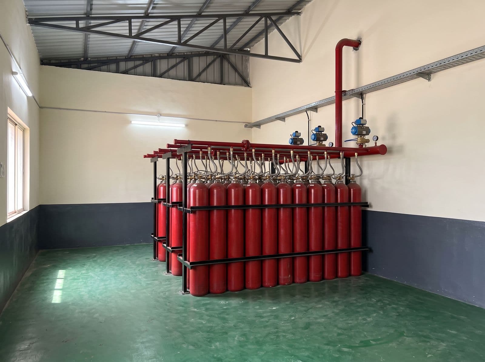 Inert gas cylinder banks with discharge manifold and selector valves in a cylinder room
