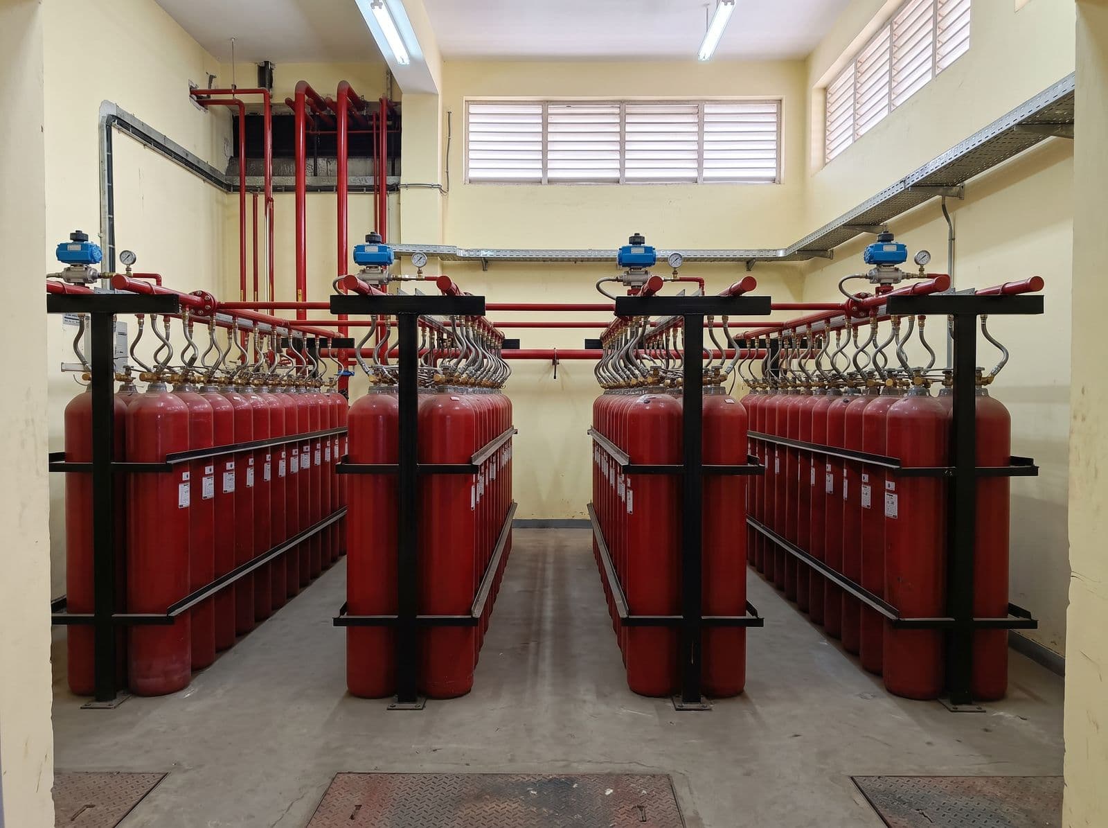 Inert gas cylinder banks with discharge manifold and selector valves in a cylinder room