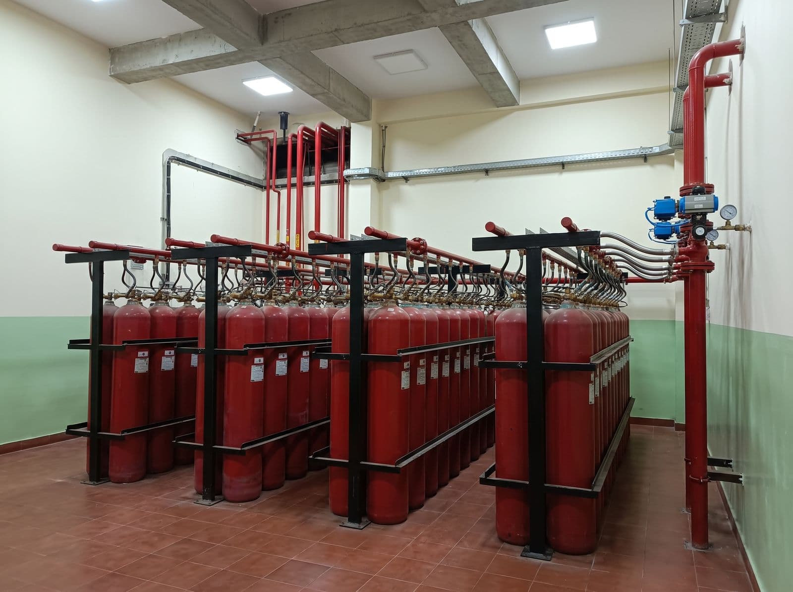 Inert gas cylinder banks with discharge manifold and selector valves in a cylinder room